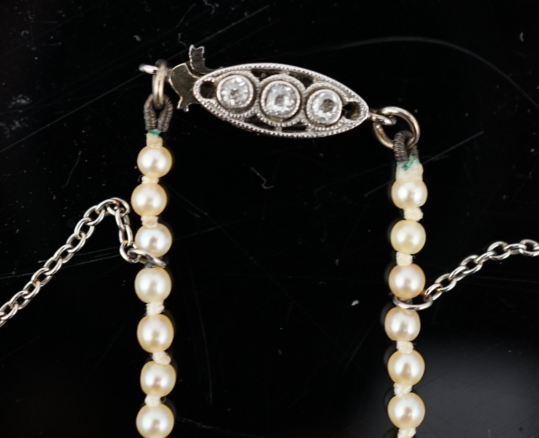 An early 20th century single strand graduated natural pearl and seed pearl necklace, with three stone diamond set clasp and Anchor Cert report dated 27/6/2014 stating an extensive sample to be natural pearls